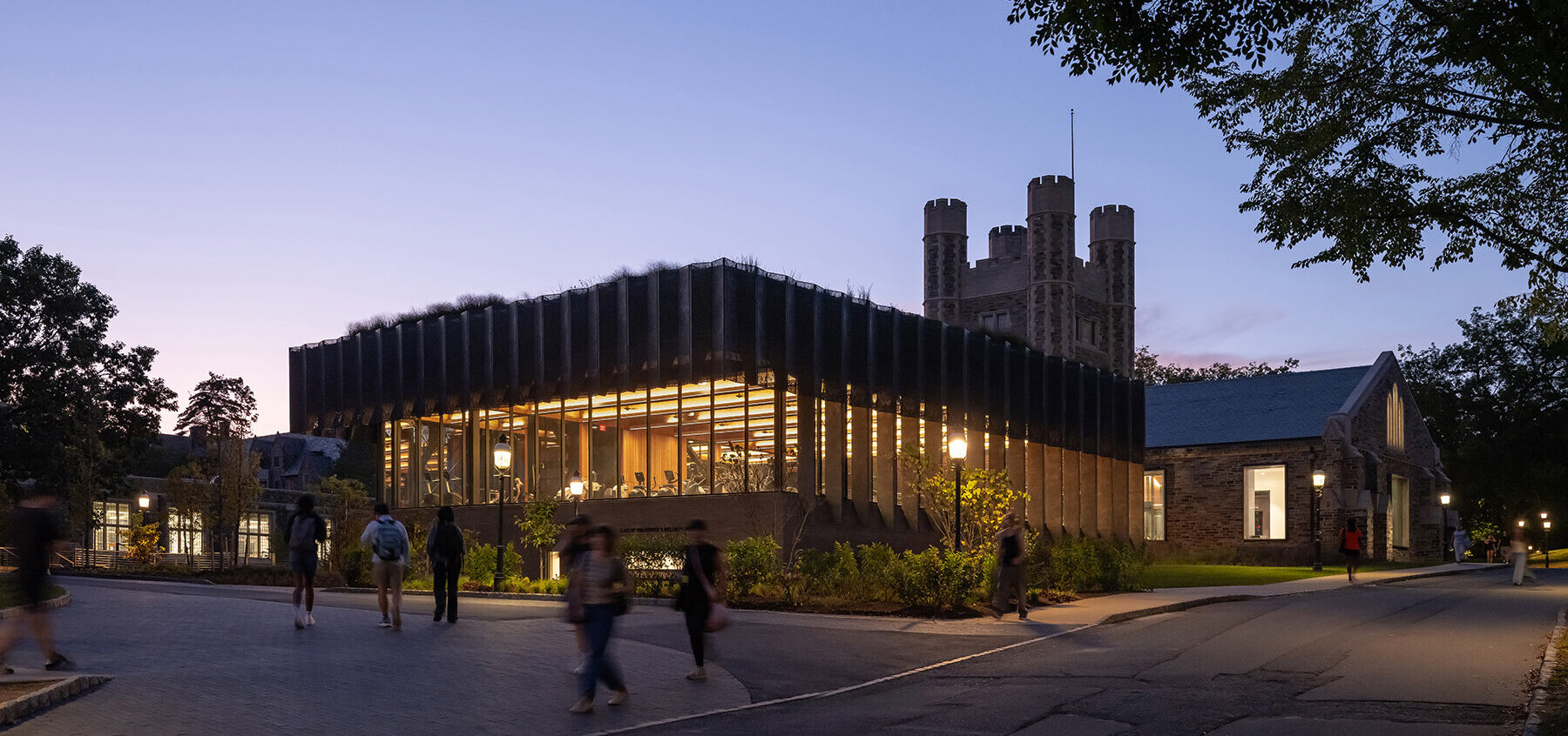 Bronze façade screen illuminated at night, creating a lantern-like appearance for the Princeton Fitness &amp; Wellness Center.